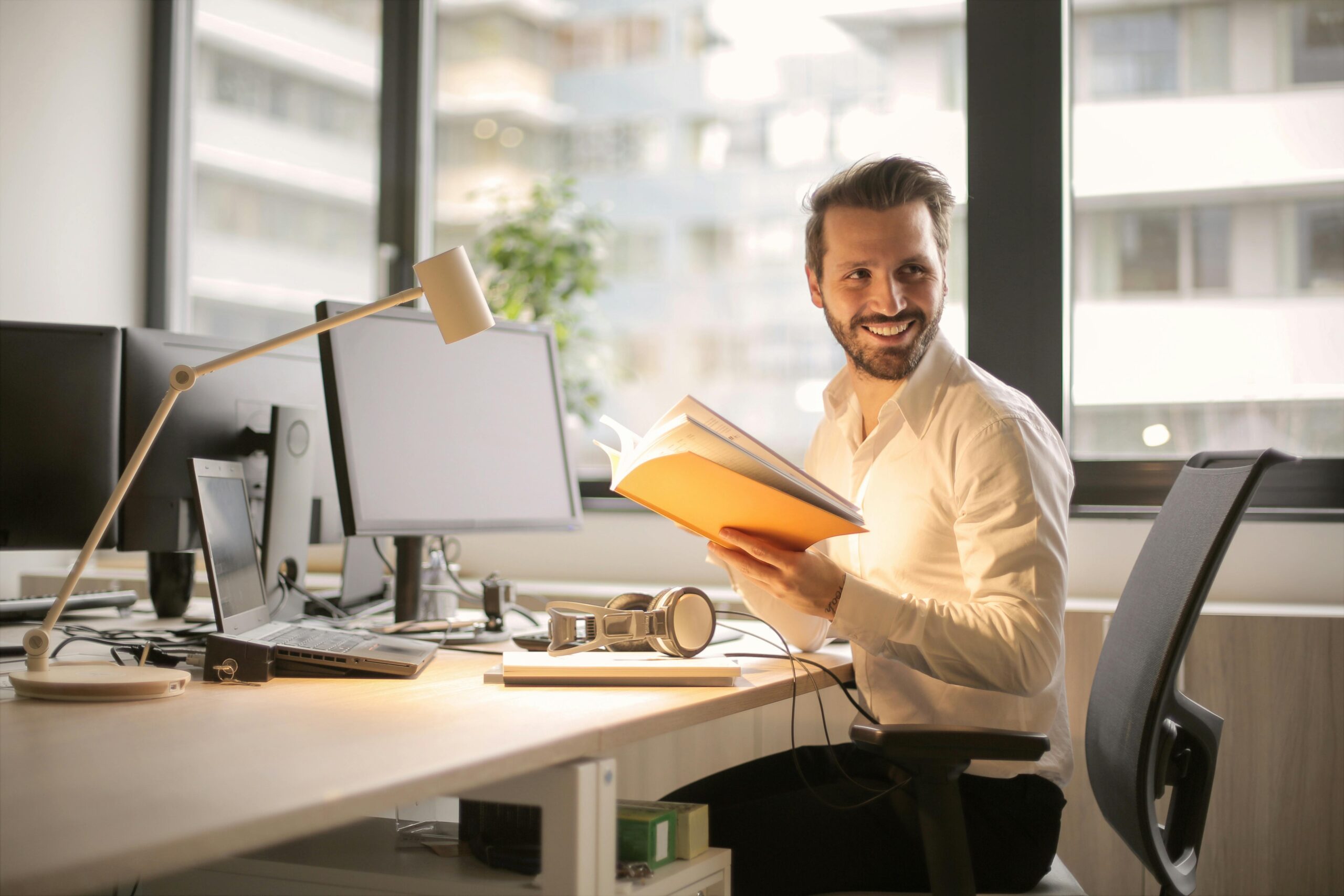 mann im office vor bildschirm mit buch in der hand